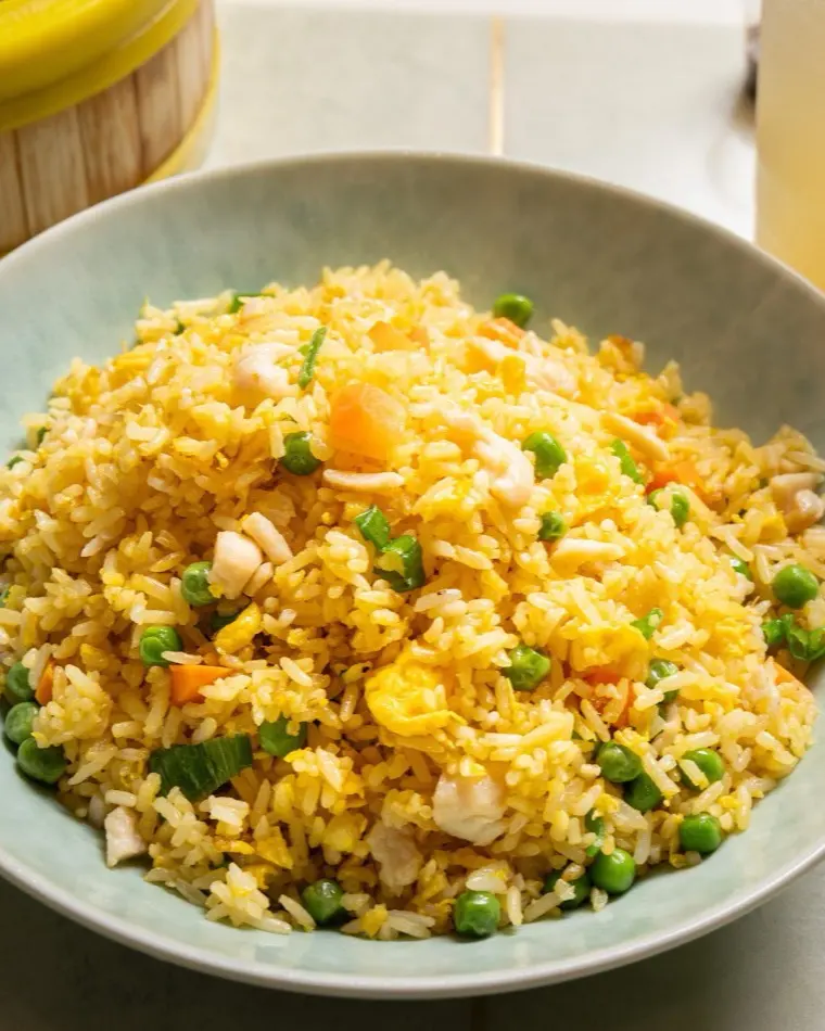 Egg fried rice with sweet peas, carrot and spring onion in a ceramic bowl