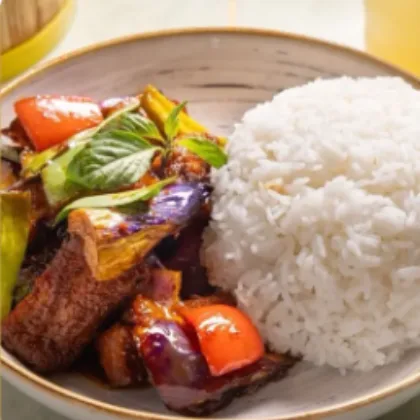 Rice plate with wok-braised eggplant, sweet peppers and basil served beside steamed white rice at Bao Express