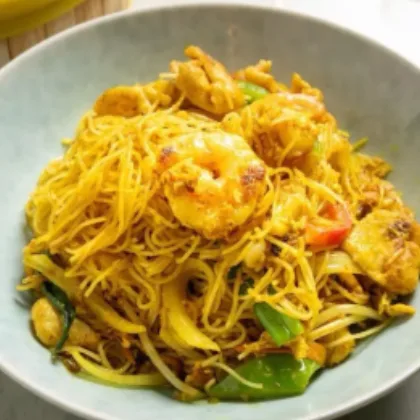 Singapore-style curry rice noodles with shrimp, chicken, bean sprouts and peppers in a bowl at Bao Express
