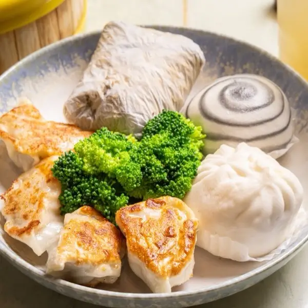 Dim sum plate with a sticky rice wrap, swirled sesame bun, pan-fried pot stickers and broccoli