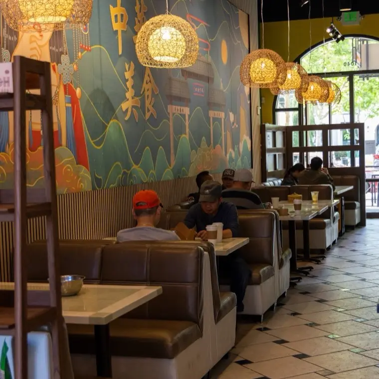 The Bao Express dining room with cushioned booths, lantern pendants and a hand-painted mural