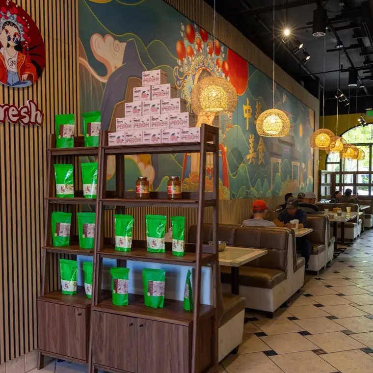 Display shelving and takeaway packaging set against the painted mural wall at Bao Express